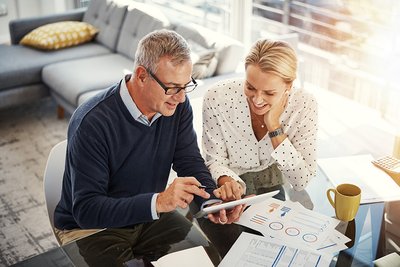 Digitizing the budgeting process Shot of a mature couple using a digital tablet while going through paperwork at home