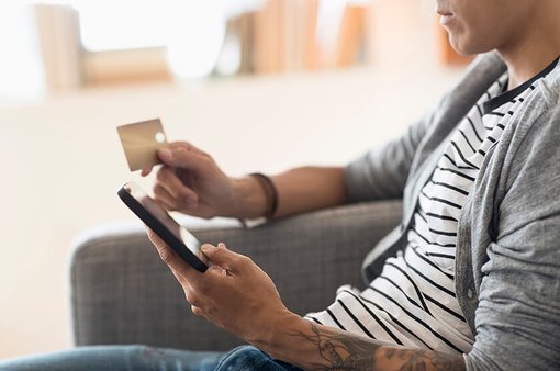 man shopping on mobile device at home holding credit card man shopping on mobile device at home holding credit card